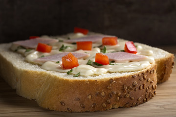 Close up of one slice of bread with cream cheese, ham and red pepper