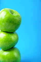 Stacked Ripe Green Apples on Blue Background Arranged in Border. Vegan Food Healthy Lifestyle Vitamins Concept. Poster Banner Streamer Template with Copy Space. Creative Conceptual Image