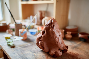 Large piece of red clay closeup on worktop at the potter workshop, close-up, shallow depth of field