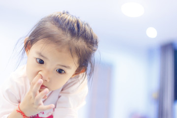 Little girl picking a nose between watching something in tablet in her house.