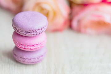 Tender french dessert macaroons with rose flower on wooden background