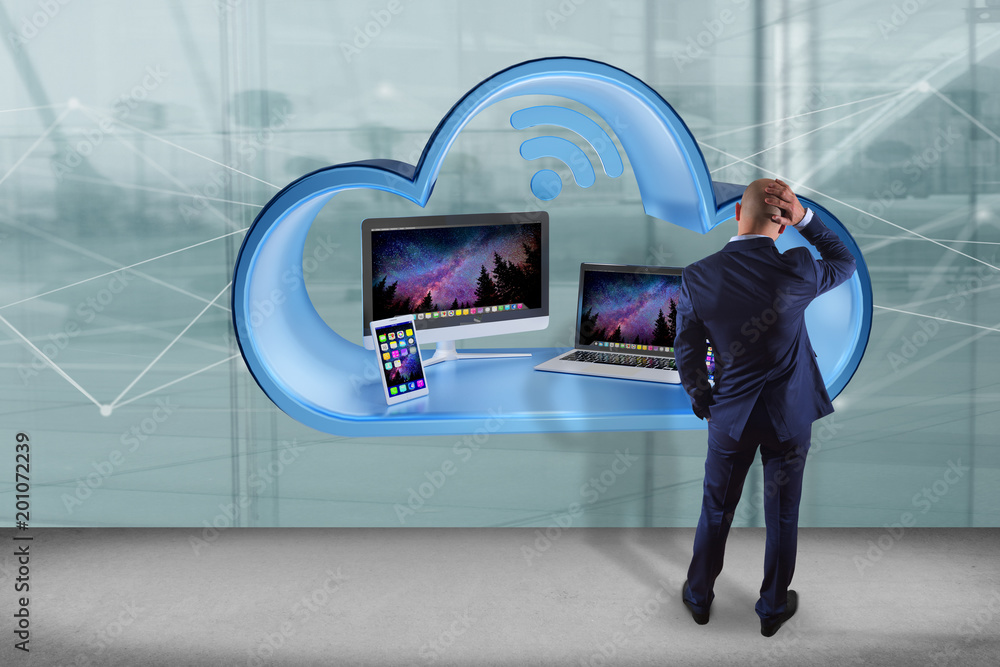 Aufkleber businessman in front of a wall with devices like smartphone, tablet or computer displayed in a cloud