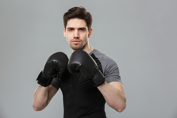 Serious young sportsman boxer make sport exercises wearing gloves.
