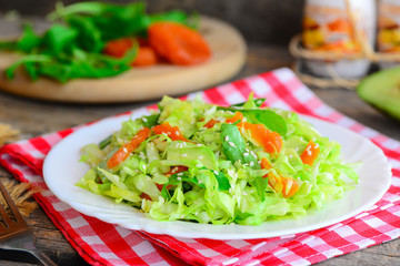 Vegan avocado coleslaw. Homemade coleslaw salad with avocado, dried apricots, arugula and sesame on a plate and on a wooden table. Raw vegan food diet. Closeup