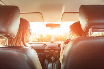 Fototapeta premium Enjoying woman and friend driving in red car summer vacation, holidays, travel, road trip and people concept .