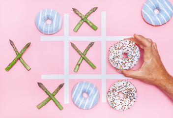 Playing in tik tak toe game with donuts and asparagus. Health nutrition concept image