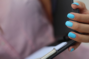 Female hands with blue nails opening the notebook
