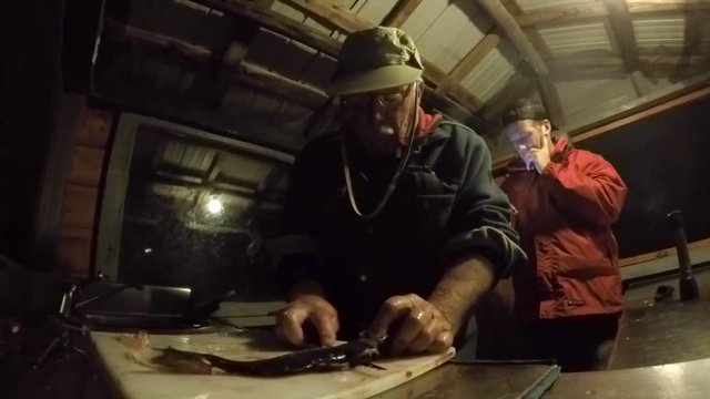 fisherman filletting fish in hut gopro