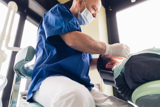 Dentist carrying out dental procedure on male patient