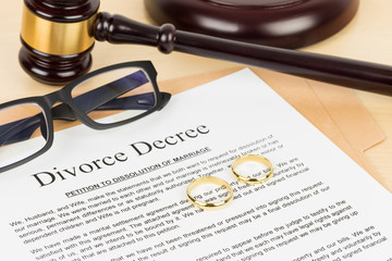 Wooden judge gavel, golden rings, and divorce decree; document is mock-up