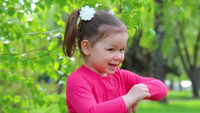 Adult mother tickles her shy 4 years old little daughter while playing outdoors in green spring or summer park.
