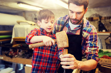 family, carpentry, woodwork and people concept - father and little son with hammer and chisel...