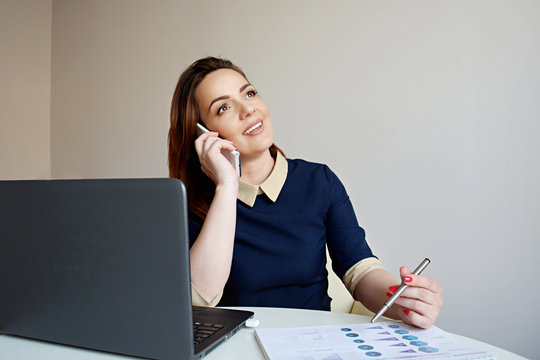  Attractive businesswoman working on laptop and making phone call