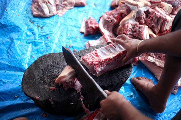 Butcher cut raw meat of a pig with a knife at table in the slaughterhouse
