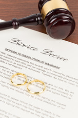 Wooden judge gavel, golden rings, and divorce decree; document is mock-up