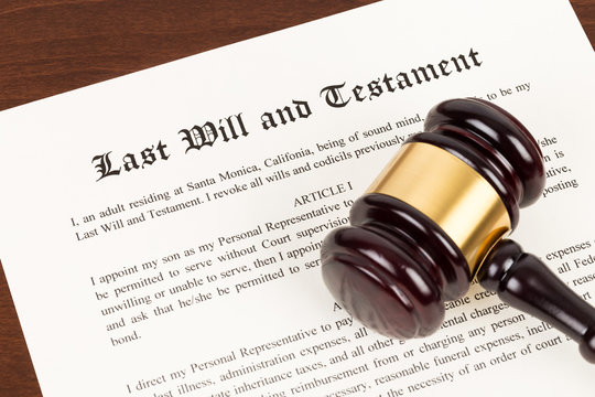 Last will and testament on yellowish paper with wooden judge gavel; document is mock-up