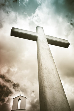 Concrete christian cross against a dramatic cloudy sky - concept image