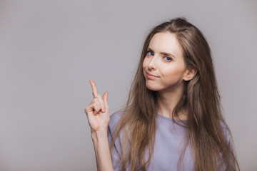 Look there! Adorable brunette female model with attractive look, indicates with fore finger at...