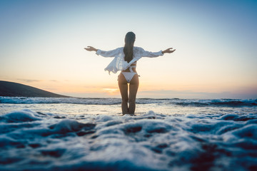 Woman enjoying the freedom of her vacation at the sea in a sunset mood