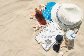 Hat, sunglasses, sunscreen, mojito on the beach, on white sand with space for writing or advertising