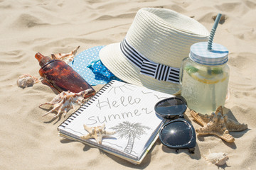 Hat, sunglasses, sunscreen, mojito on the beach, on white sand