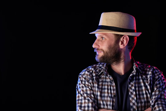 Profile Closeup Portrait Of Bearded Man Looking To The Side Wearing Fedora Hat Over Dark Background, Red And Blue Backlit