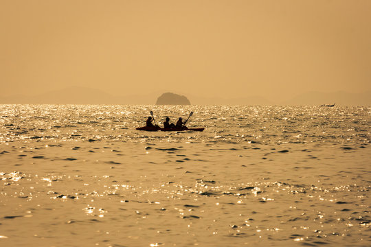 Thai long boat and a kayak at sea at sunset, with golden colors, in Railay beach, Krabi, Thailand.
