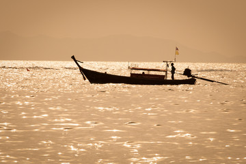 Thai long boat and a kayak at sea at sunset, with golden colors, in Railay beach, Krabi, Thailand.