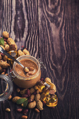 Natural peanut butter with oil in a glass jar and peanuts