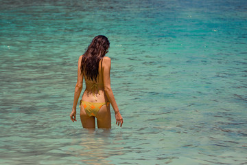 Woman model in a yellow bikini bathing in blue water at Maya Bay, Phi Phi Leh, Thailand