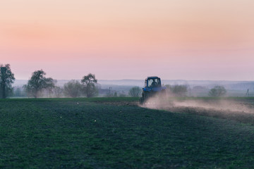 Fototapeta premium Agricultural machinery in field on the Sunset.