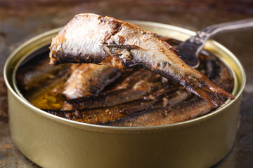 Open canned fish near fork on rustic background