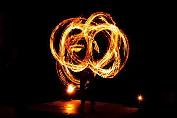 Street artist fire juggling performance. Light painting and long exposure picture to form trails....