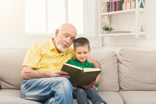 Senior man reading book for his grandchild
