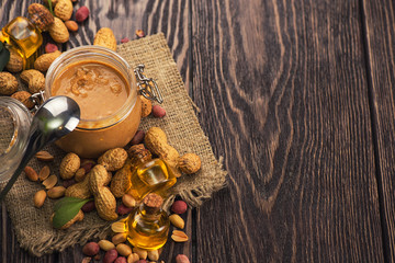 Natural peanut butter with oil in a glass jar and peanuts