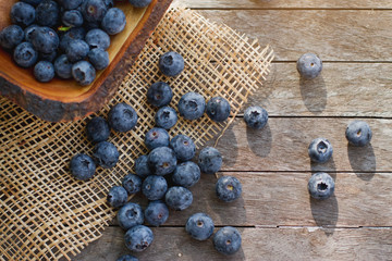 Freshly picked blueberries in morning. Juicy and fresh blueberries with green leaves on wooden table.