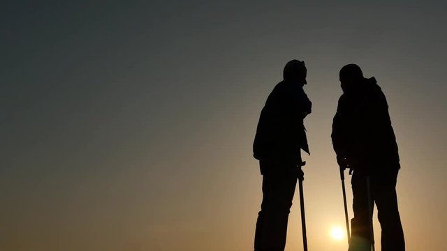 elder man gives helping hand to cripple silhouettes