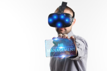 Fototapeta premium Business, Technology, Internet and network concept. Young businessman working in virtual reality glasses sees the inscription: HR management