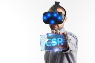 Fototapeta premium Business, Technology, Internet and network concept. Young businessman working in virtual reality glasses sees the inscription: CSR