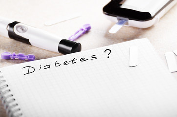 Personal blood glucose meter notebook and lancet on the table