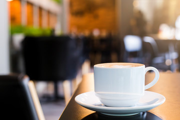 Latte Coffee in a cup on wooden table and Coffee shop blur background