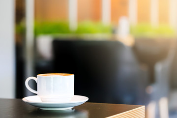 Latte Coffee in a cup on wooden table and Coffee shop blur background