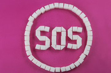 SOS sign in round from sugar cubes on pink magenta red background