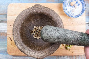 Chef pound pepper with pestle on mortar