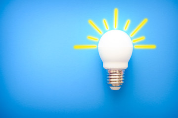 led light bulb with yellow rays on blue background 