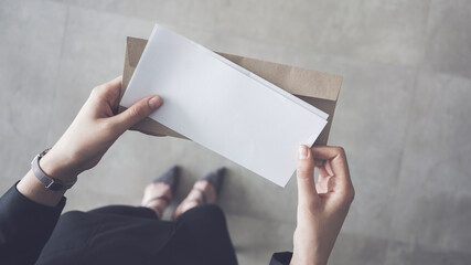 Stand up woman holding white folded a4 paper and brown envelope