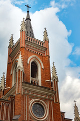 The building of the Catholic church with crosses and the spire on the building on a background of white clouds and a blue sky.