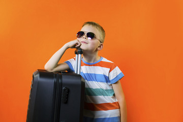 cute boy with a suitcase on a bright orange background