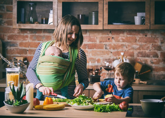 Happy young family, beautiful mother with two children, adorable preschool boy and baby in sling...