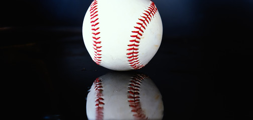 Baseball ball with reflection on black background, shows athletic team sport